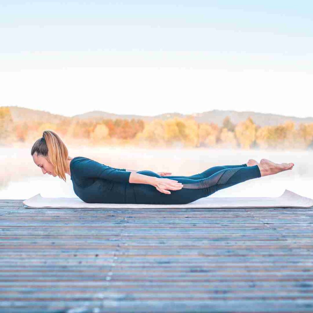 women doing yoga Locust Pose (Shalabhasana) on mat in mountain